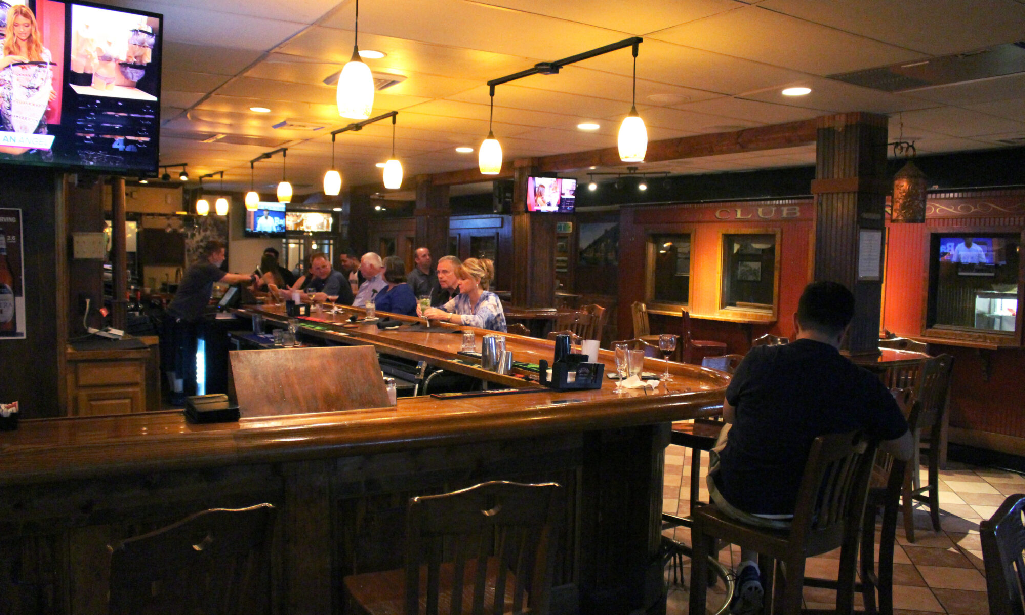 Bar interior with patrons and hanging lights.